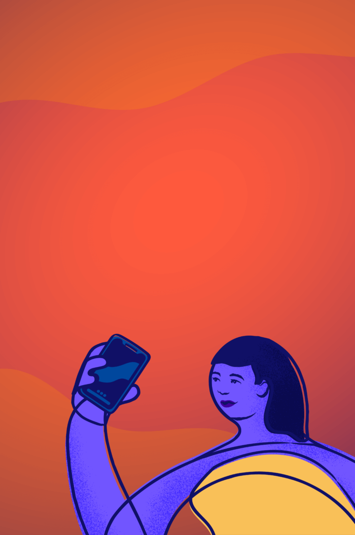 A young LGBTQ+ person holds their phone in front of an orange background.