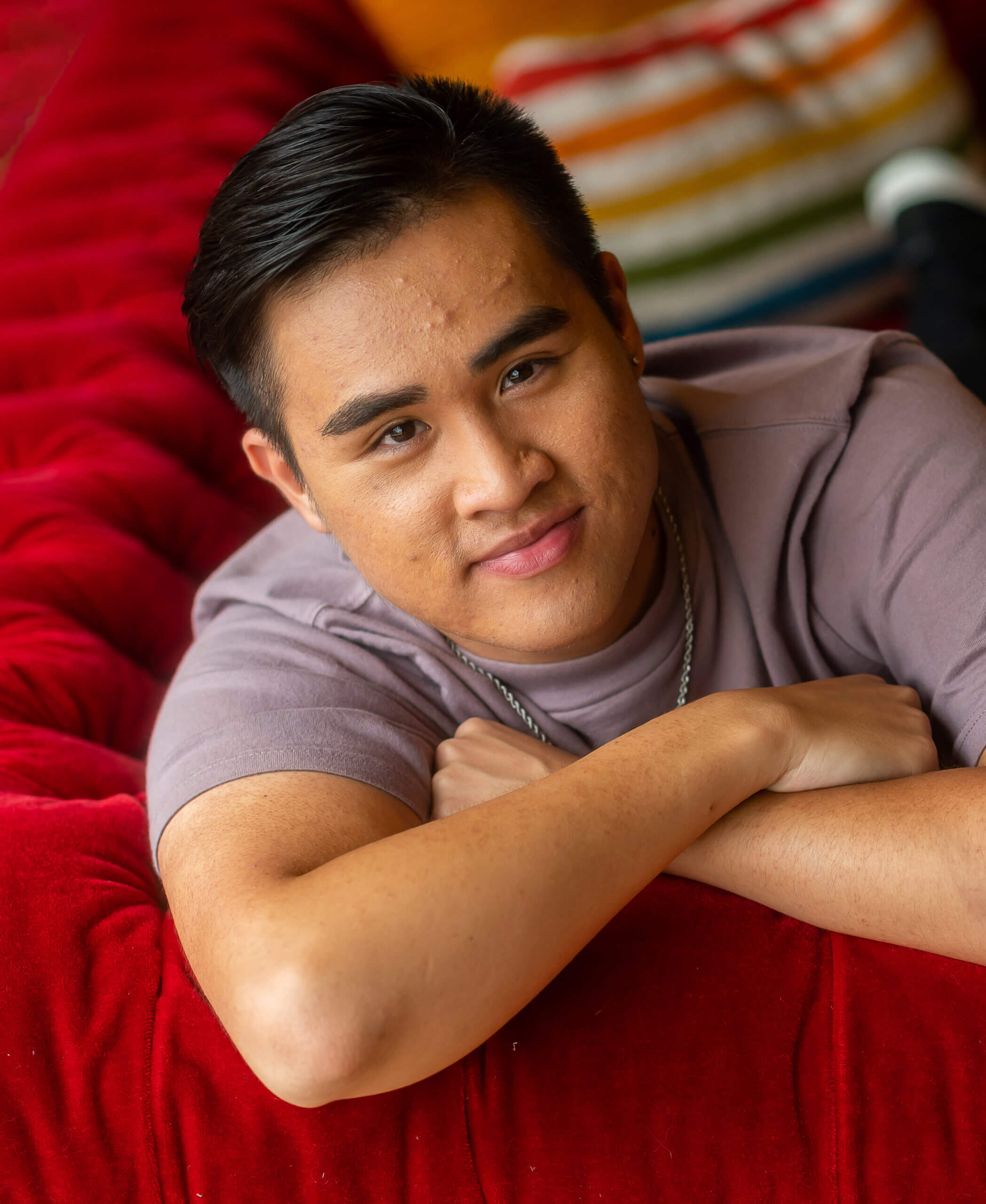 An LGBTQ+ young person lies forward on a couch.